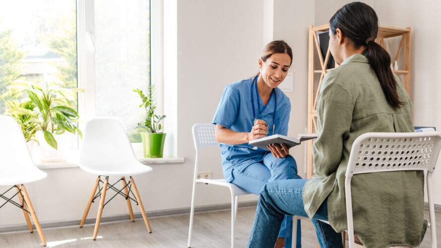 White woman doctor talking with patient while working in her office
