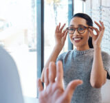 A customer buying, testing or trying on glasses at an optometrist store or shop. Health care eye wear professional picking or selling a pair of new eyeglasses to a young female client or patient