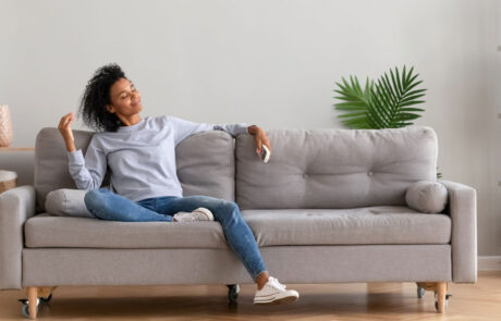 African young relaxed woman sitting on couch breathing fresh air