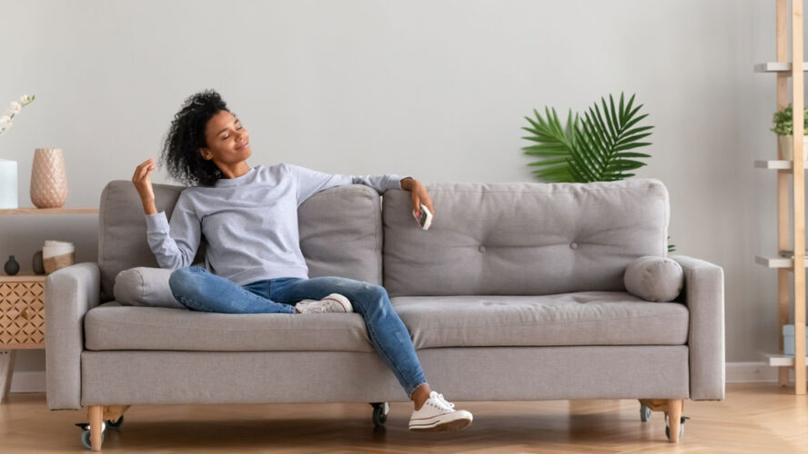 African young relaxed woman sitting on couch breathing fresh air