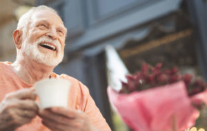 Laughing elderly man drinking tea outdoors