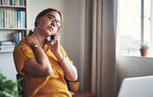 Cropped shot of an attractive young businesswoman sitting alone in her home office and feeling stressed while using her cellphone