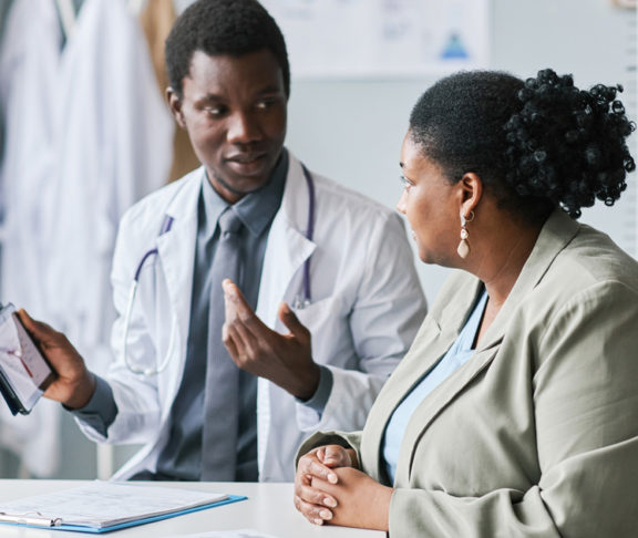 Side view portrait of a woman listening to doctor in clinic