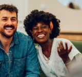 Young multiracial couple smiling because solved conflict at couple therapy session with a counseling adviser and. Diverse spouses being happy with a psychologist advises. Copy space.