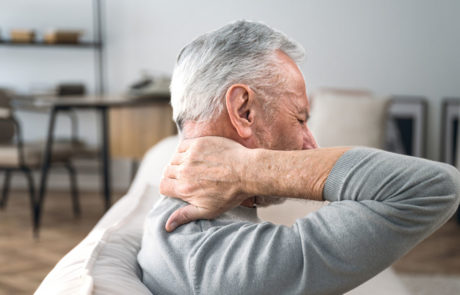 Elderly man rubbing hard pain in neck and massaging tense muscles