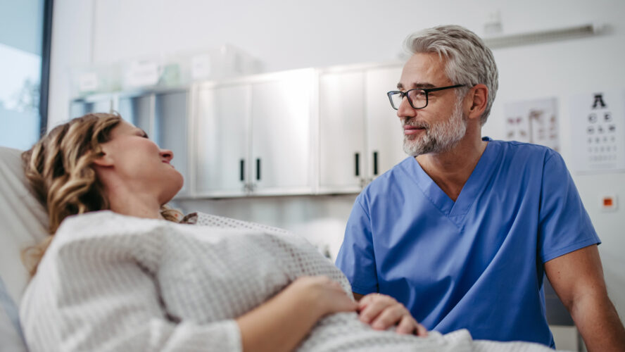 Doctor talking with worried female patient, emotional support before surgery. Friendly male doctor reassuring the patient.
