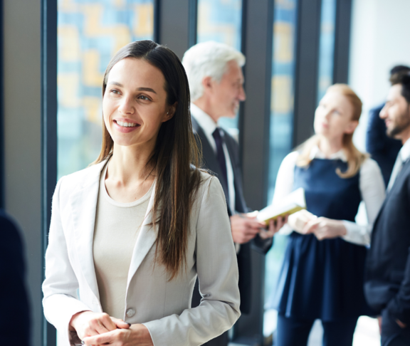 Smiling pretty young business lady in jacket talking to colleague and discussing business forum topics during break