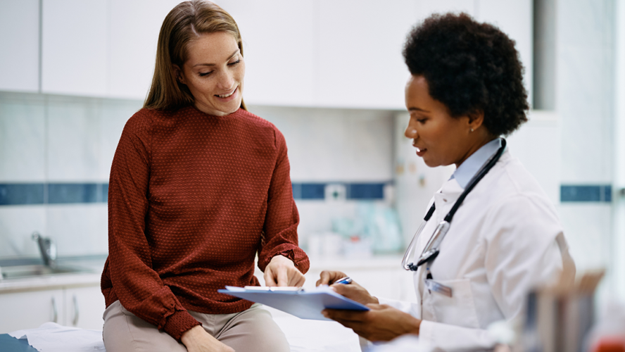 Happy woman going through her medical data with black female doctor at the clinic