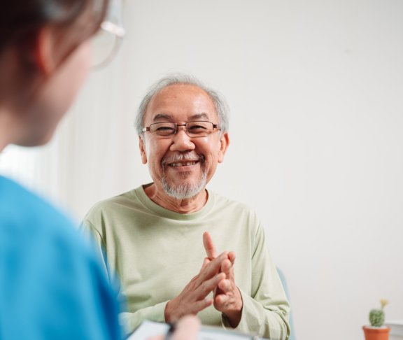 Asian caregiver talking senior male patient checkup in living room at home. Older elderly man consults after physical therapy. Nurse assistance rescue concept